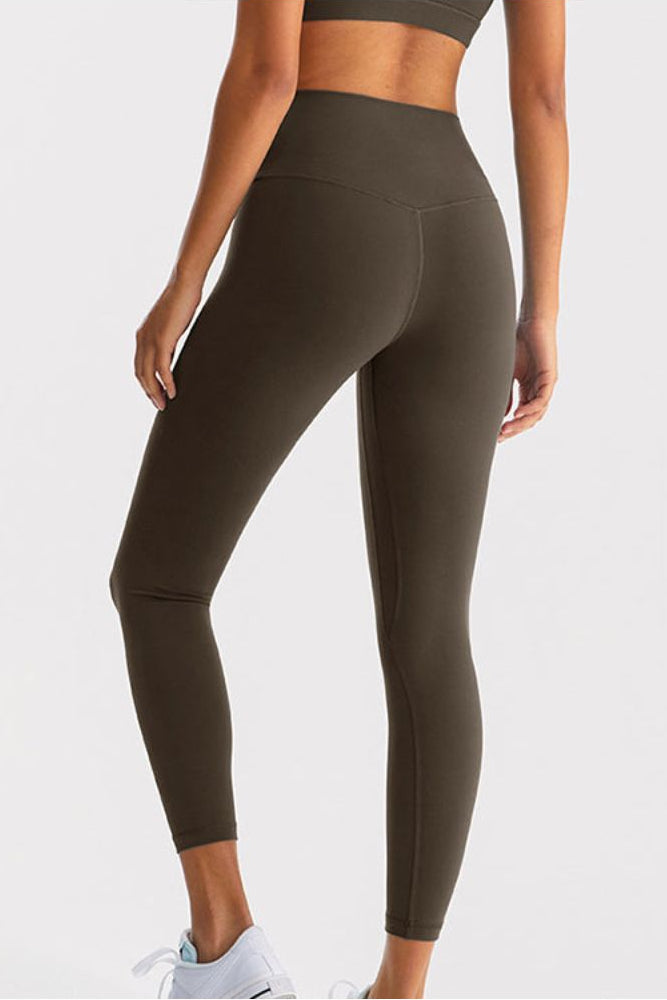 Person wearing olive green leggings on a light gray background