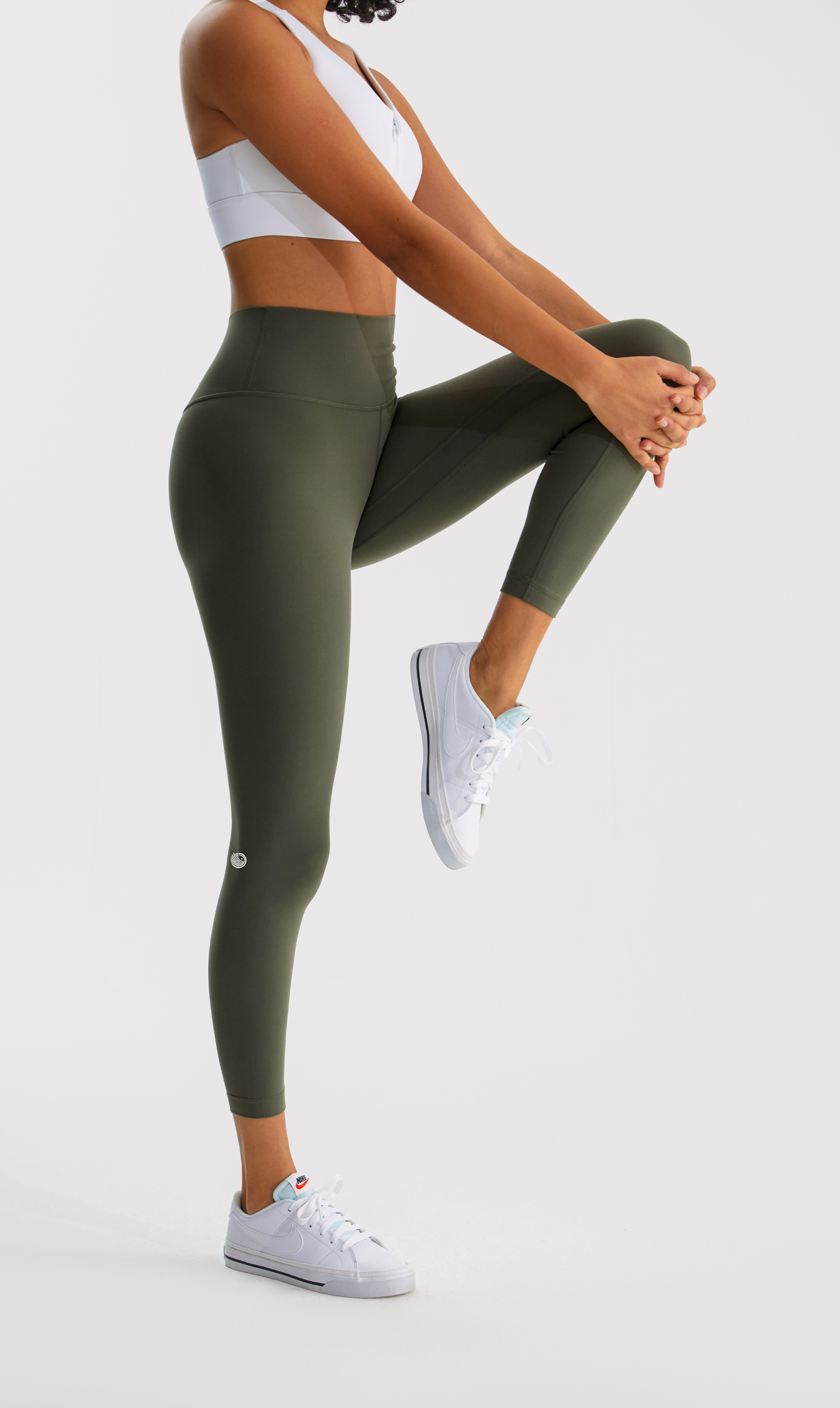 Person wearing green leggings and white sneakers on a white background