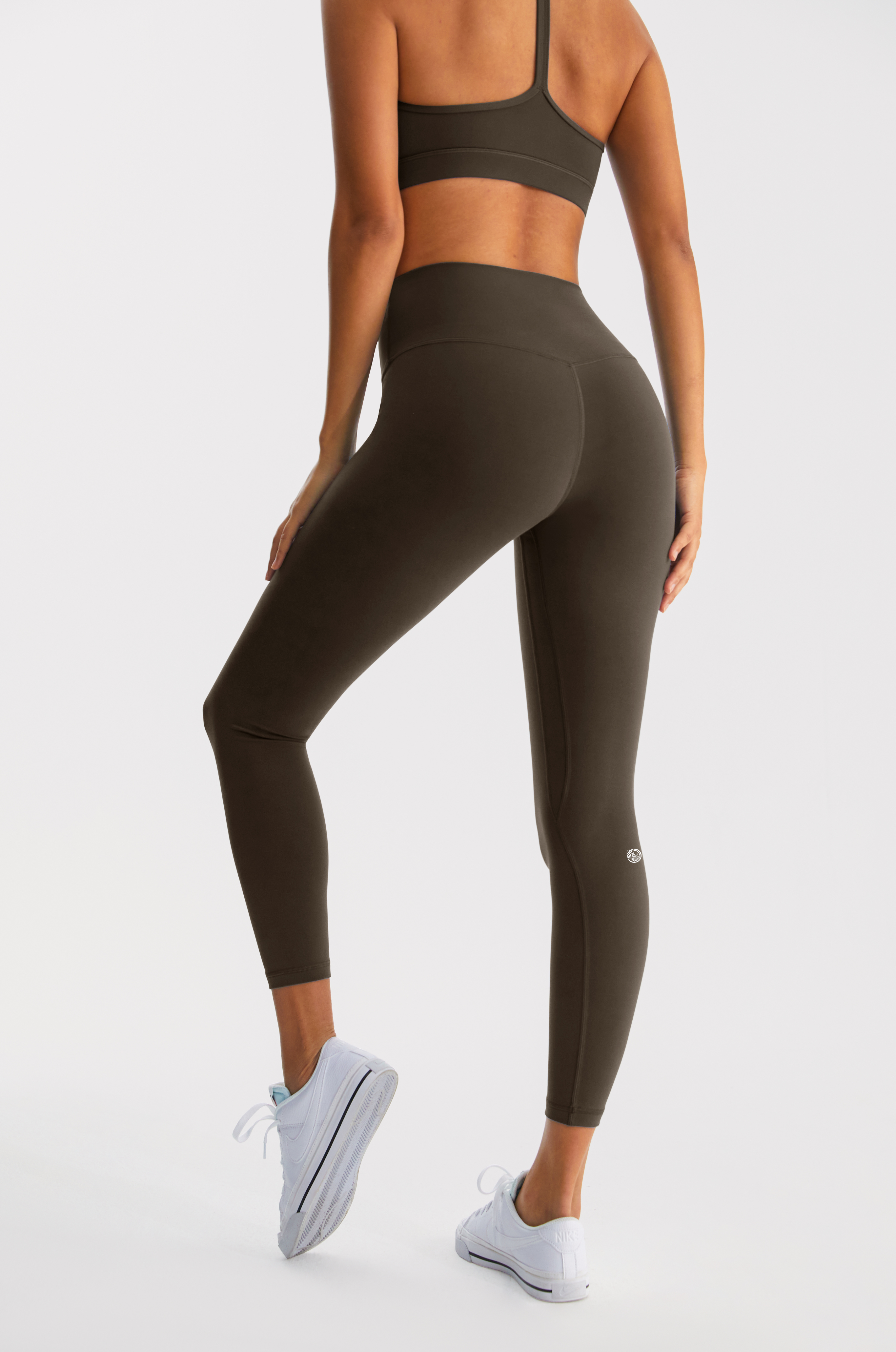 Person wearing a black sports bra and leggings on a white background