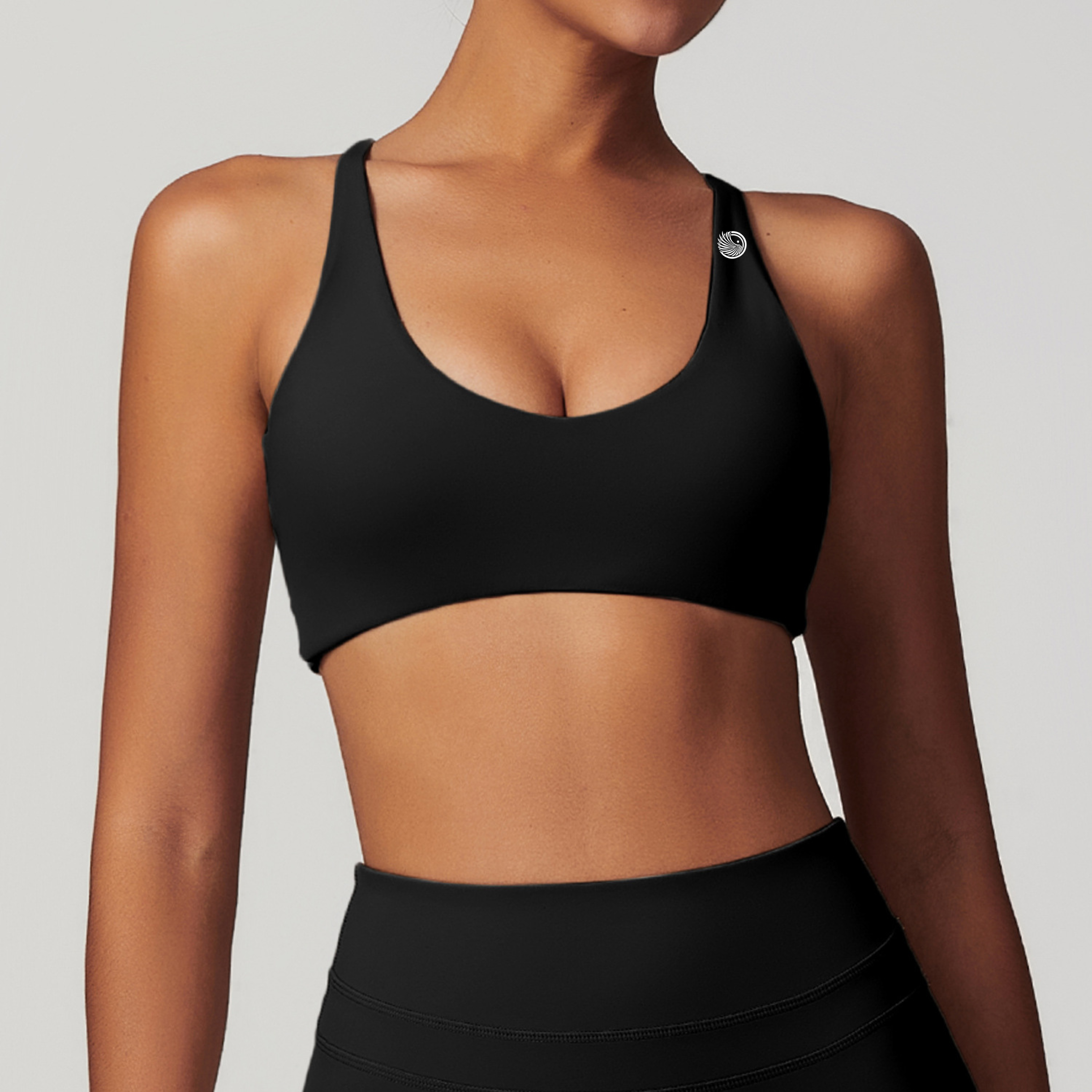 Person wearing a black sports bra and leggings on a light gray background