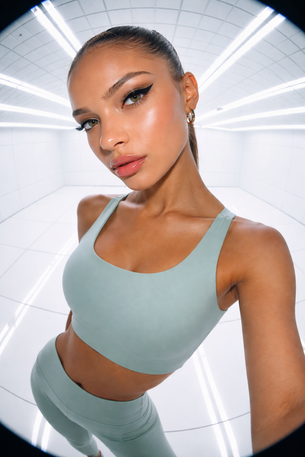 Woman wearing a light green sports bra and leggings against a white background