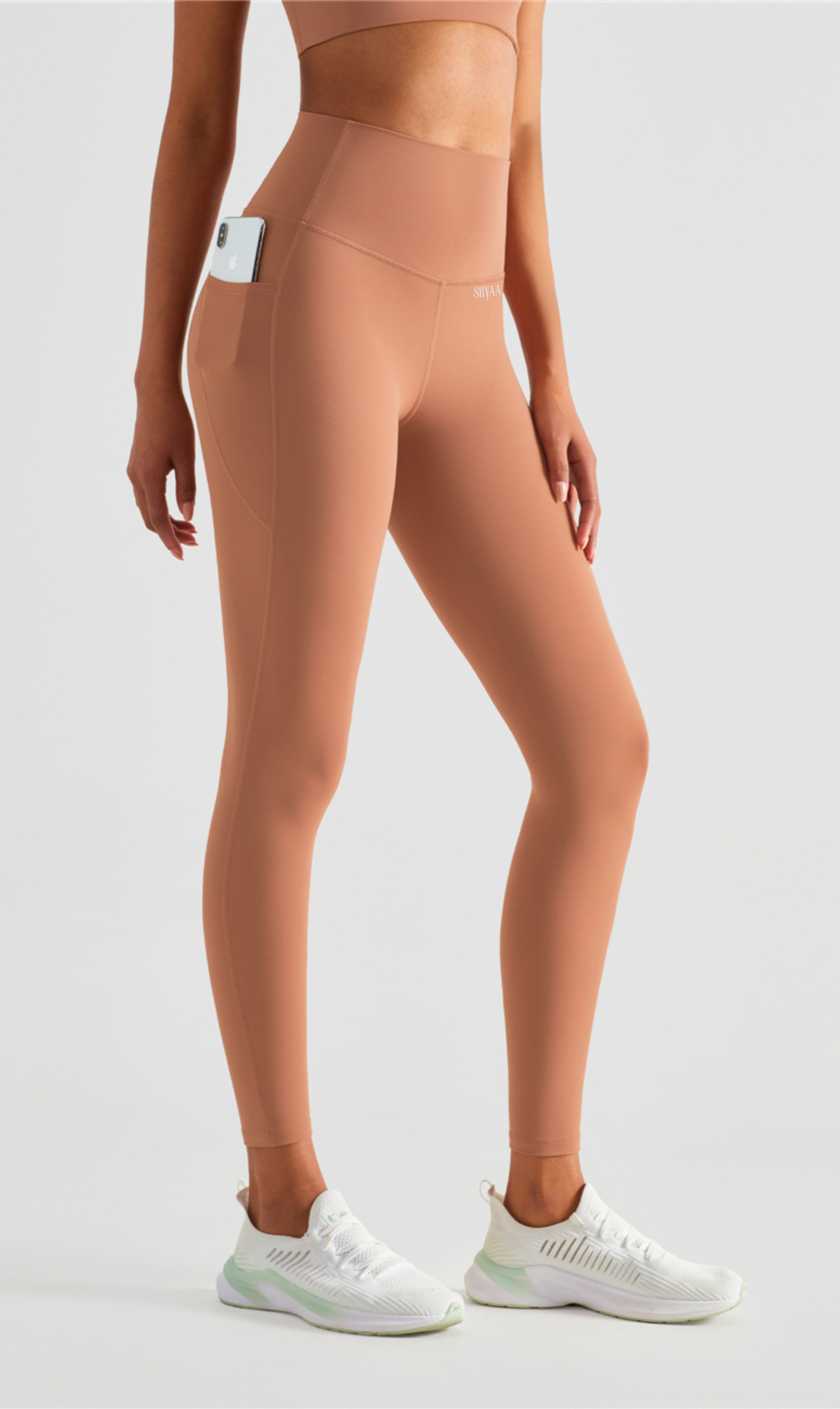 Person wearing beige leggings and white sneakers on a light gray background